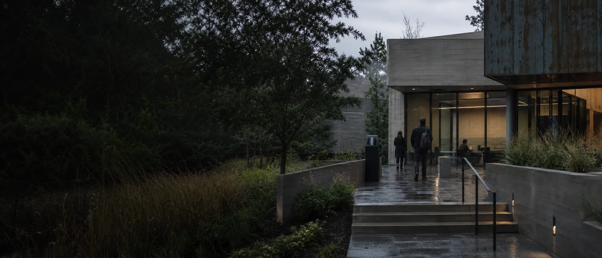 Professionals entering a contemporary concrete institution through a visible, human-scale threshold
